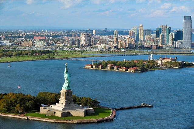 Aerial view of the Statue of Liberty and Ellis Island with the New York City skyline in the background.