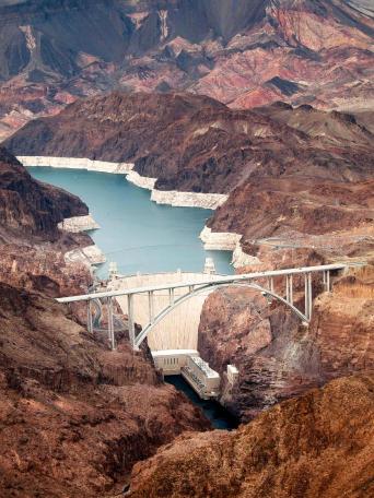 An image of Hoover Dam with the Colorado River in the background, showcasing the dam's structure and the surrounding landscape.