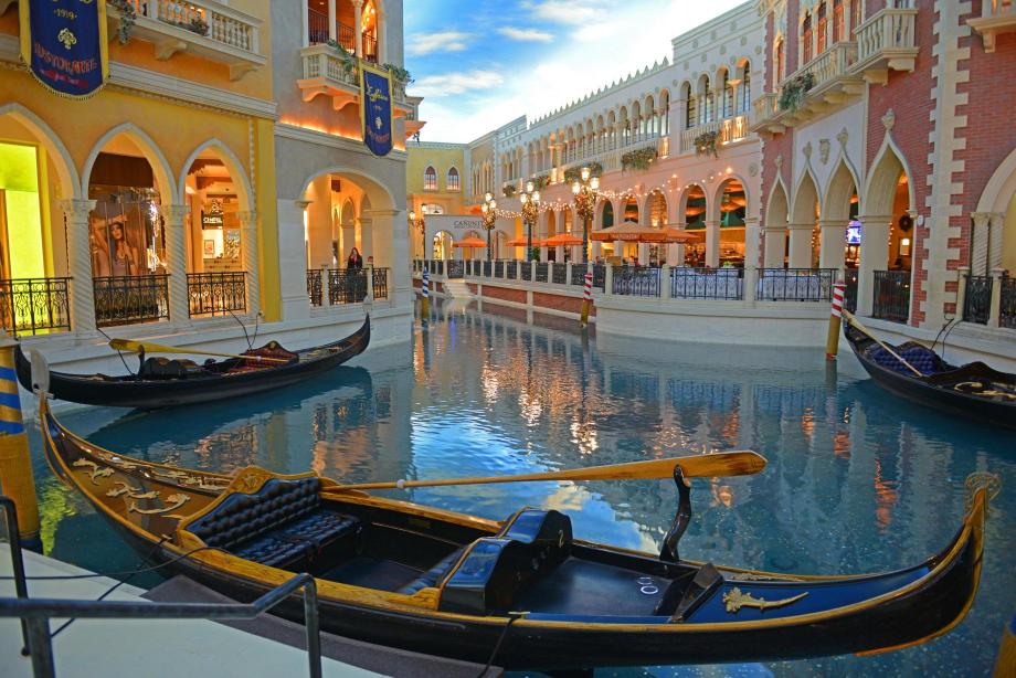 An artificial canal in a shopping mall with gondolas and buildings resembling those in Venice.