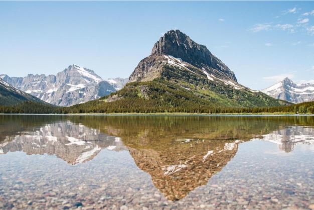 A clear reflection of a mountain in the still waters of Swiftcurrent Lake in Glacier National Park.