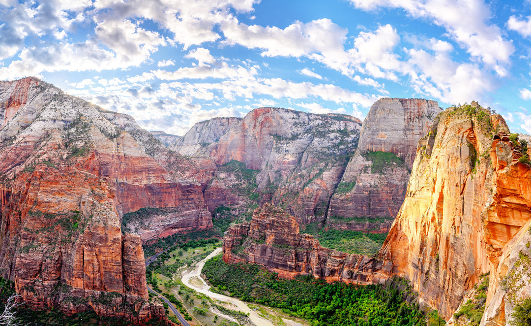 A landscape photograph of Zion National Park showing a scenic view of the park's mountains and valleys with a blue sky overhead.