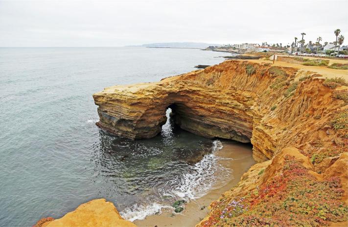 A natural park with cliffs over-looking the ocean, featuring a distinct arch formation in the cliff.