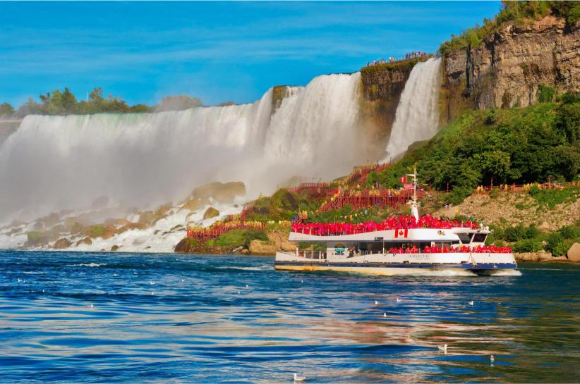 A sightseeing boat on the water near Niagara Falls, with the American Falls in the background.
