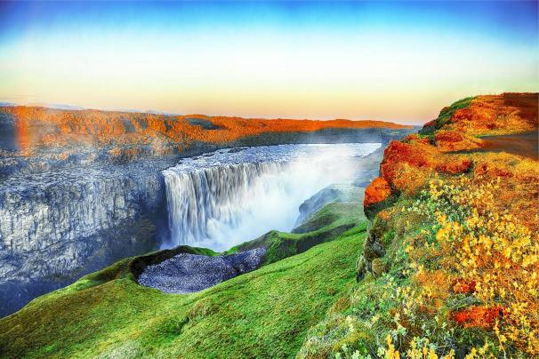 A vibrant image depicting Niagara Falls with autumn colors on the trees and a clear blue sky.