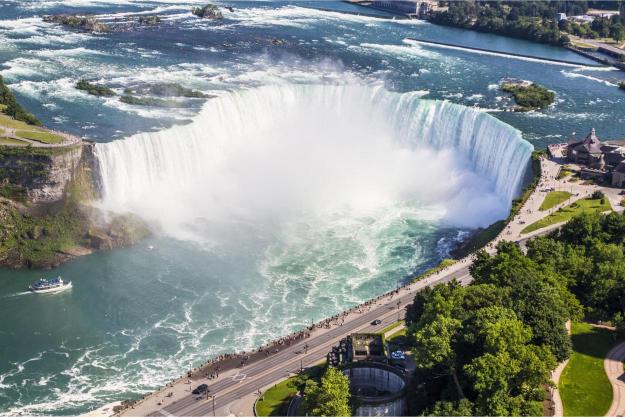 An aerial view of Niagara Falls with a focus on the waterfalls and the surrounding greenery.