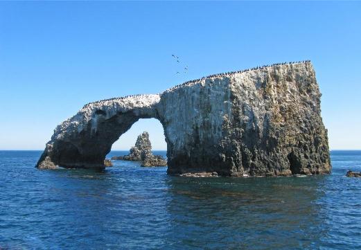 A natural rock arch in the ocean, likely part of the Channel Islands National Park.