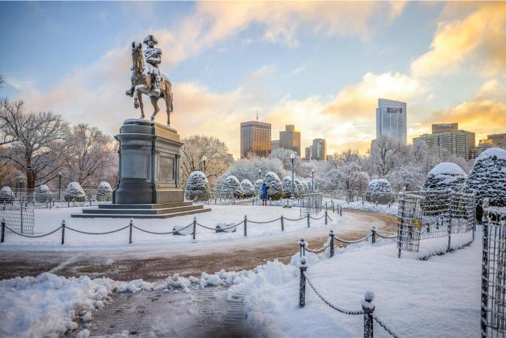 A statue of George Washington on horseback, located in a snowy urban park with buildings in the background.