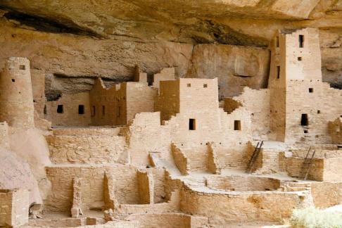An image depicting the ruins of Mesa Verde National Park, showcasing sandstone cliffs with ancient built structures.
