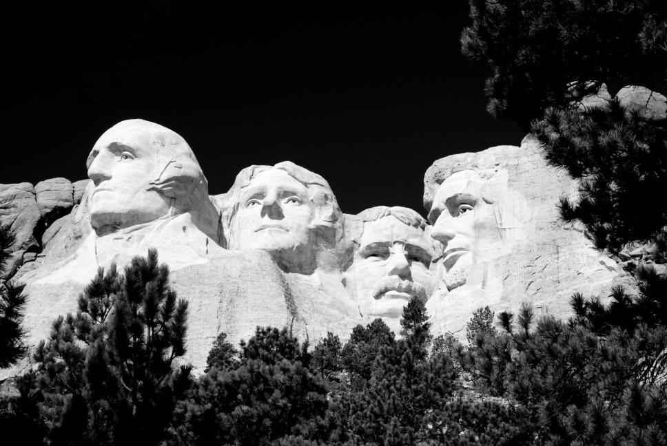 A black and white image of Mount Rushmore, showcasing the sculptures of four presidents' faces carved into the mountain.