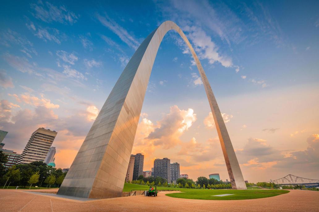 The Gateway Arch in St. Louis, Missouri, at sunset with the cityscape in the background.