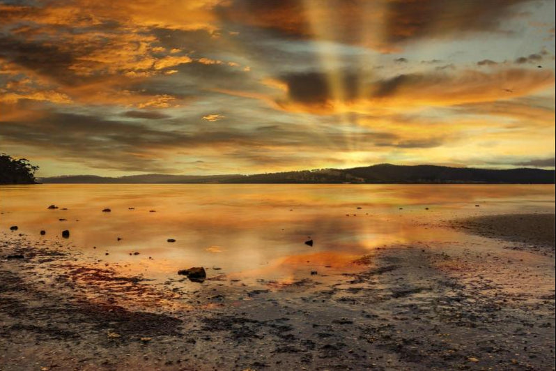 Sunset over a calm lake with reflected colors on the water's surface.