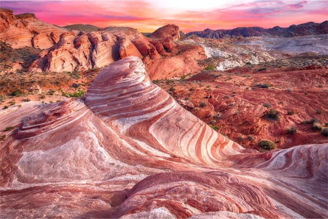 A landscape photo of the Valley of Fire with pink and orange hues at sunset.