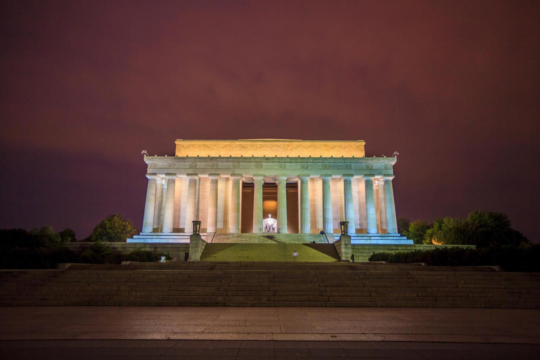 Lincoln Memorial illuminated at night, with a dark purple sky in the background.