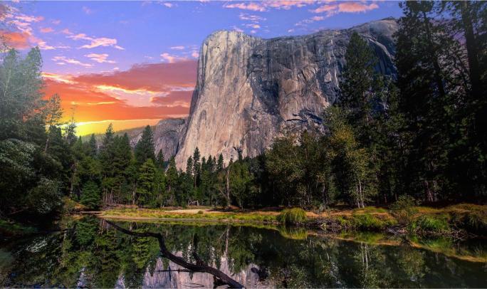 A scenic view of Yosemite National Park featuring a large granite cliff, trees, and a reflective body of water at sunset.